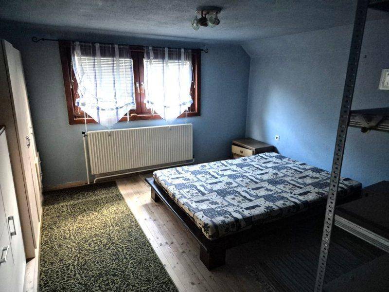 Schlafzimmer mit blau gestrichenen Wänden, Doppelbett und Fenster, mit Teppichboden.