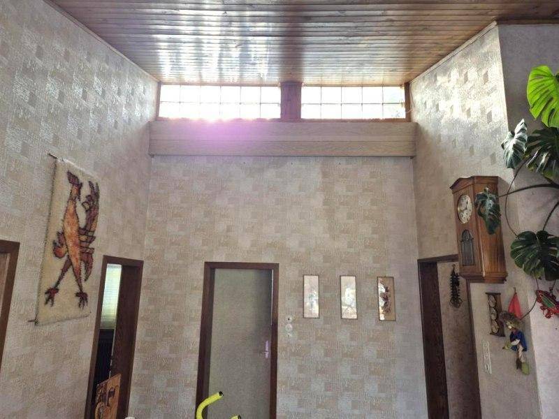 Hoher Eingangsbereich mit Holzdecke, strukturierten Tapeten und Oberlichtern für natürliches Licht.