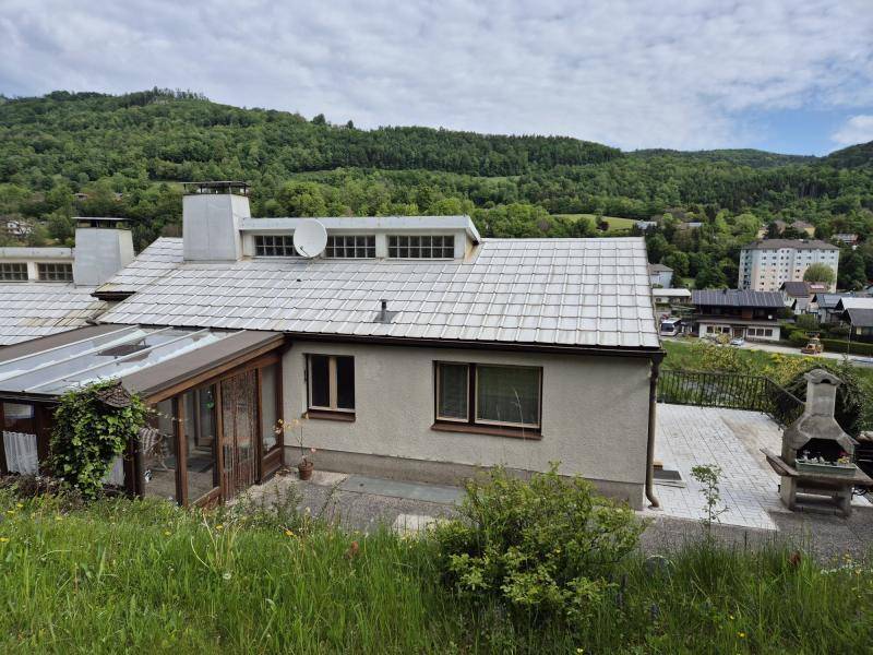 Seitenansicht des Hauses mit Wintergarten, Terrasse und Panoramablick auf die umliegende Landschaft.