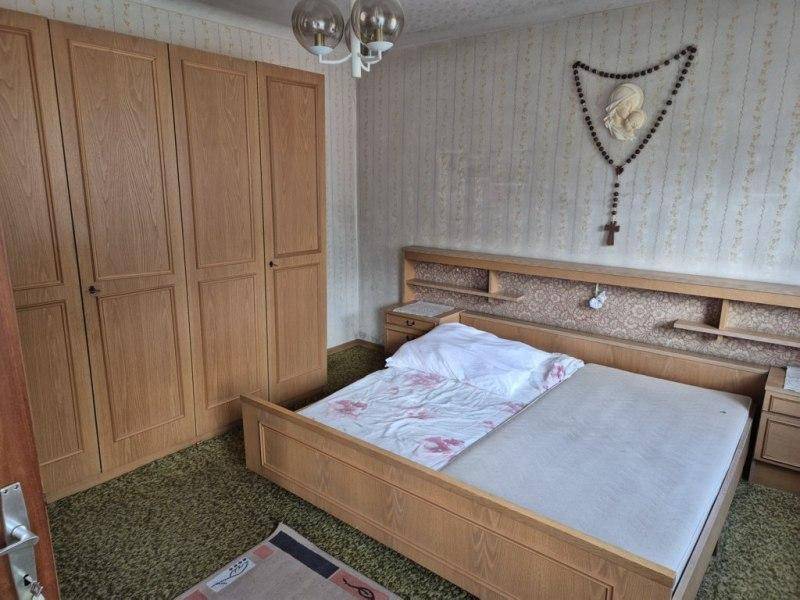 Schlafzimmer mit Doppelbett, Holzschrank und traditioneller Dekoration an der Wand.