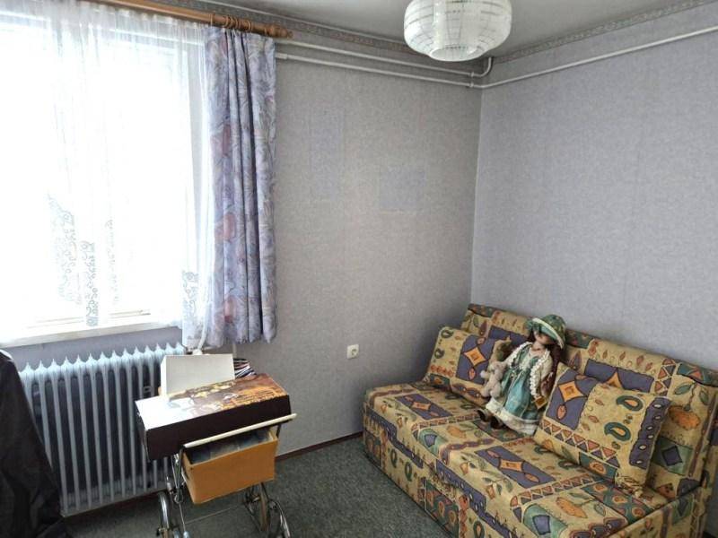Helles Zimmer mit Sofa, großem Fenster und traditionellem Heizkörper, ideal als Gästezimmer.