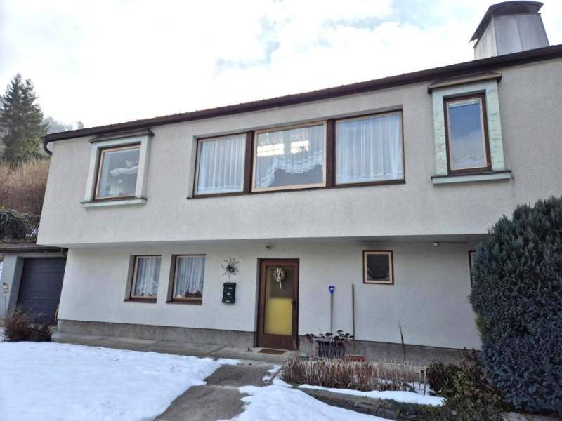 Frontansicht des Hauses mit verschneitem Vorgarten und Blick auf die umliegende Landschaft.