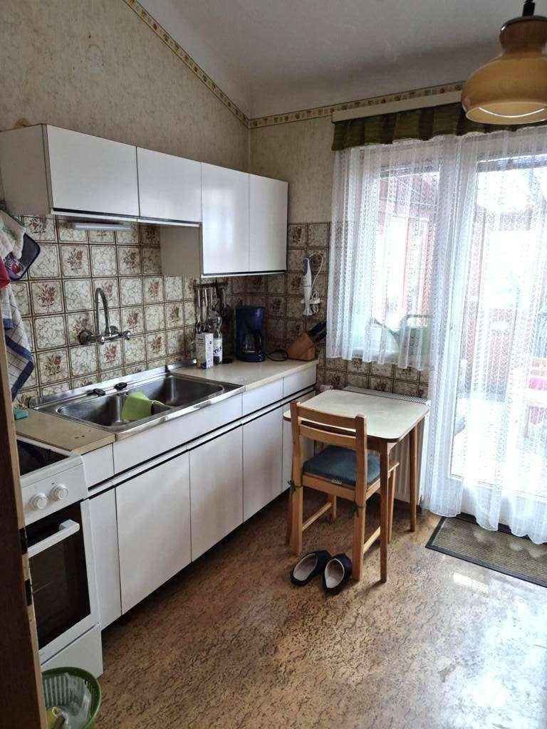 Funktionale Küche mit weißen Schränken, gemusterten Fliesen und einem kleinen Esstisch am Fenster.