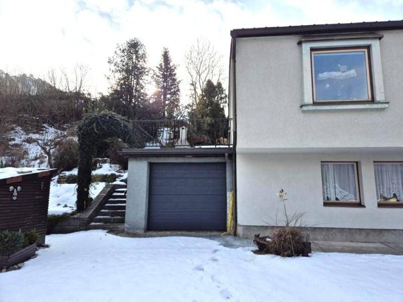 Seitenansicht des Hauses mit Garage, Treppe zum oberen Bereich und verschneiter Umgebung.
