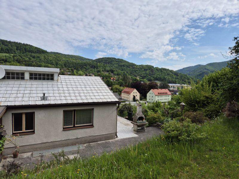Rückansicht des Hauses mit Terrasse, Grillplatz und weitem Blick auf die grünen Hügel.