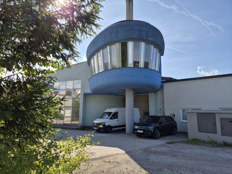 Ansicht des Gebäudes mit der einzigartigen runden Struktur und geparkten Fahrzeugen im Vordergrund.