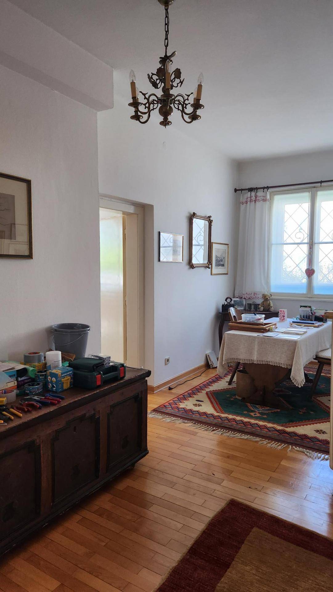 Esszimmer mit Holzboden, klassischem Kronleuchter und Blick nach draußen.