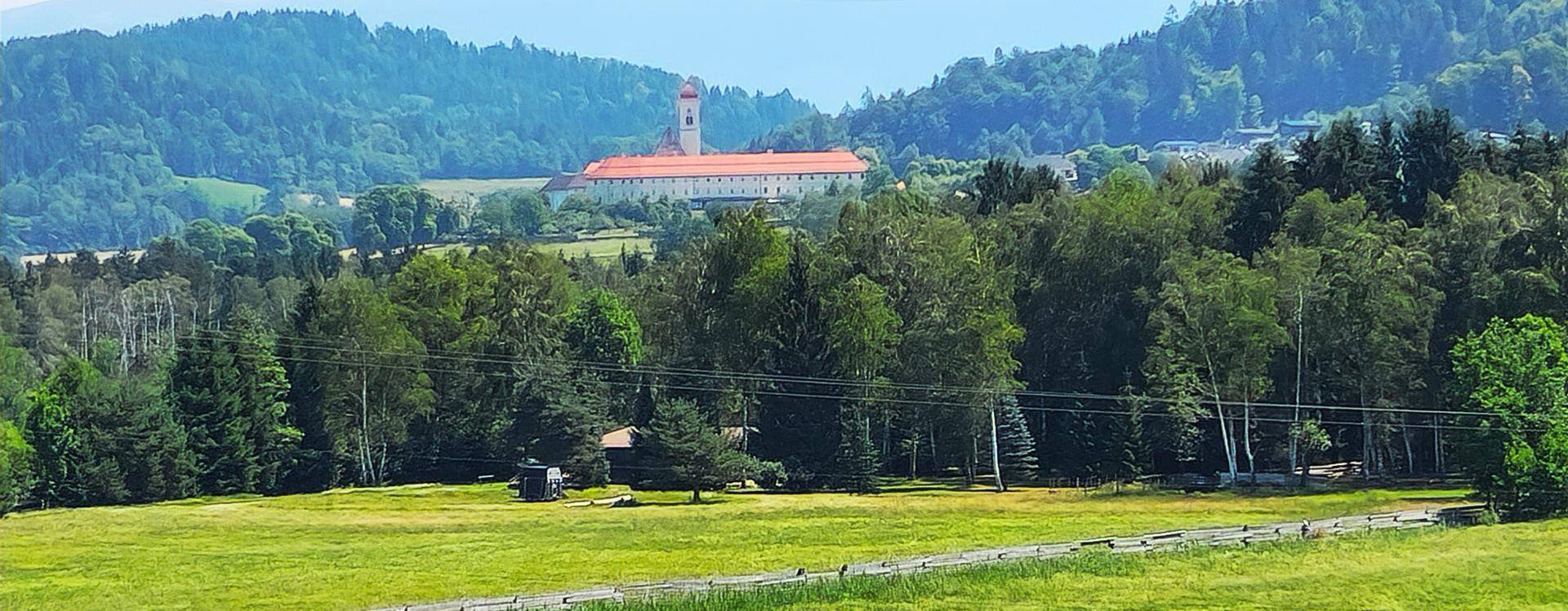 Panoramablick auf eine weite grüne Landschaft mit einem markanten Gebäude in der Ferne.