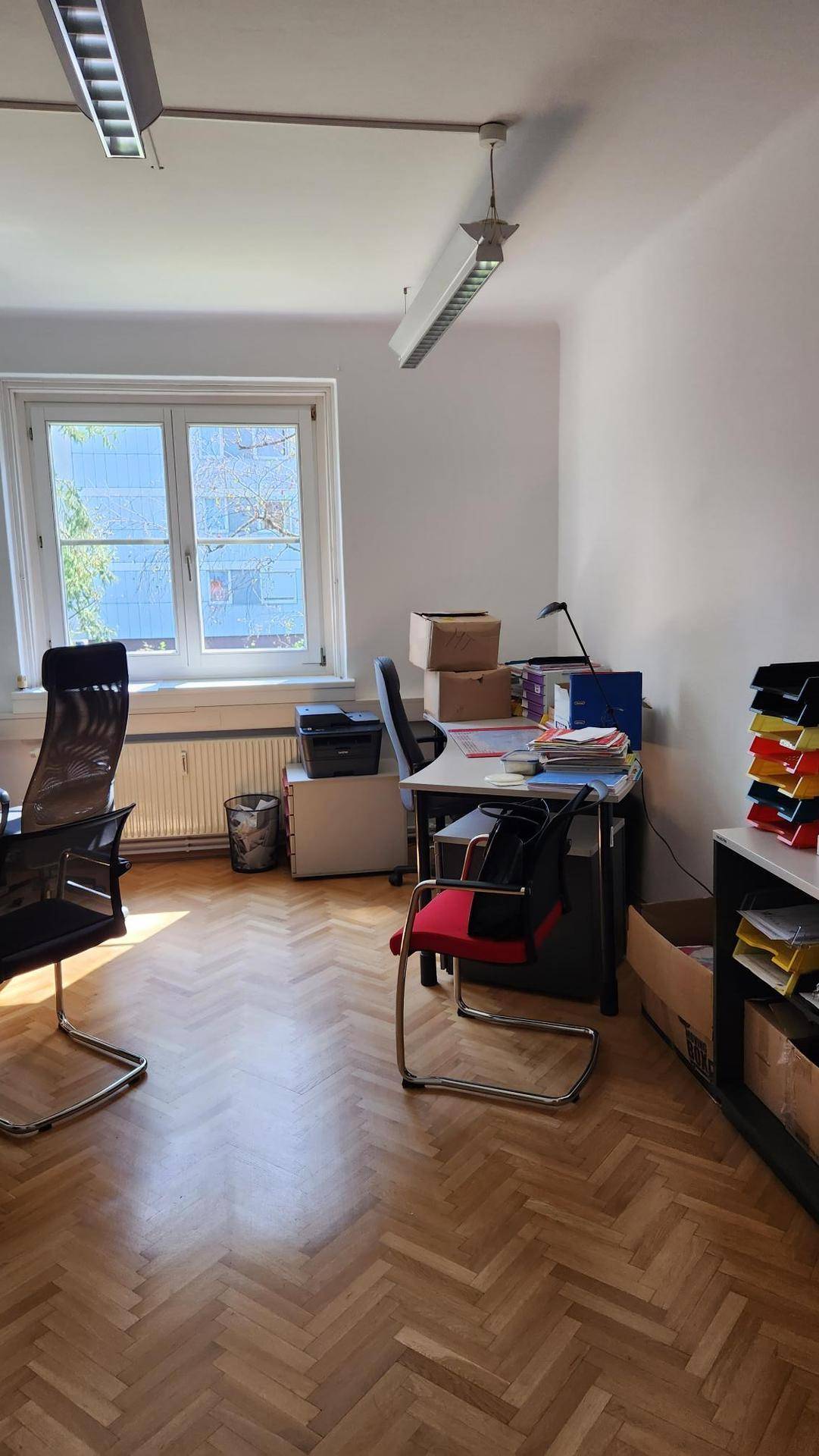 Arbeitszimmer mit Fischgrätparkett, Schreibtisch und Blick ins Grüne.