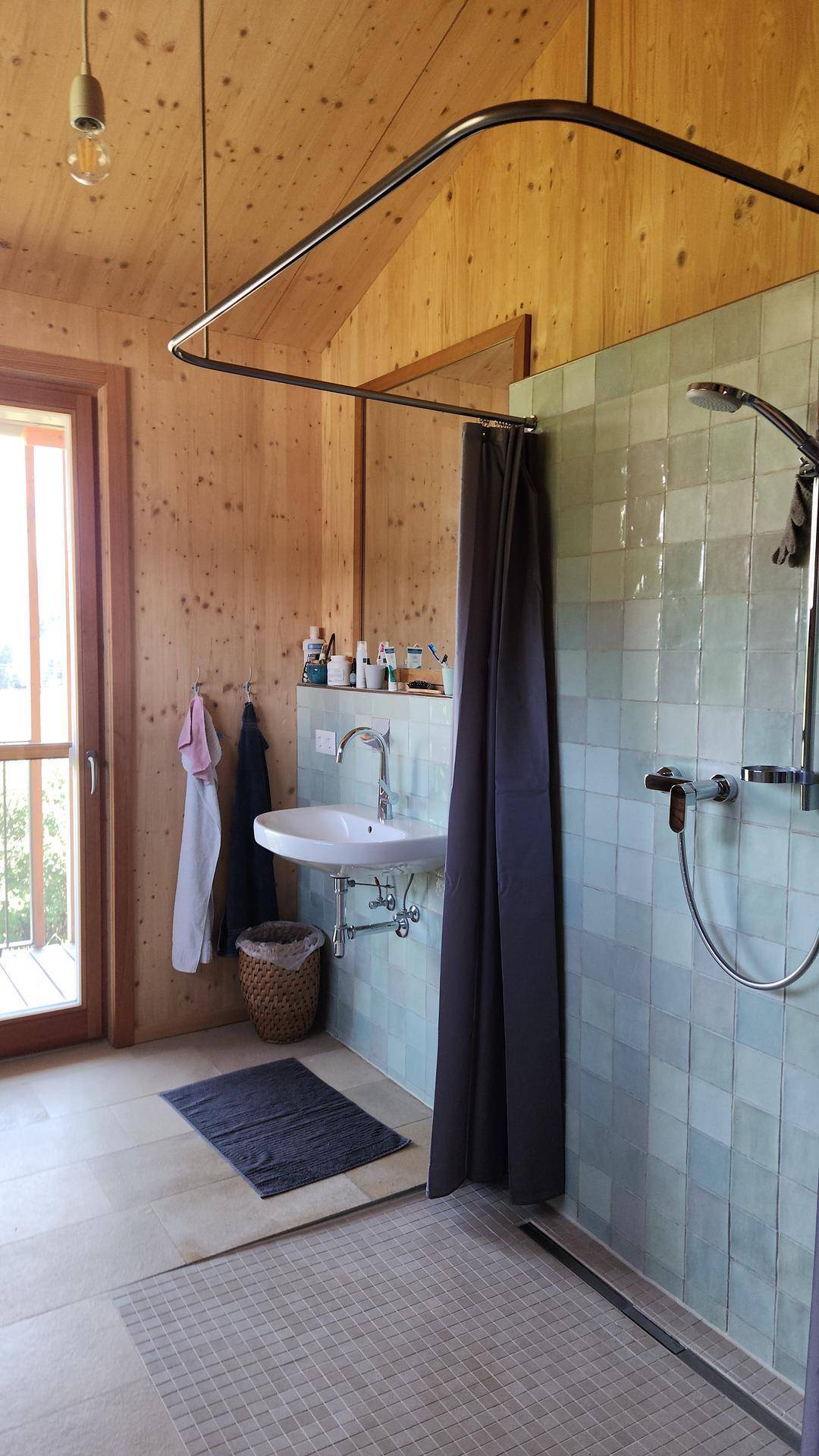 Modernes Badezimmer mit Holzwänden, ebenerdiger Dusche und Fenster mit Ausblick.