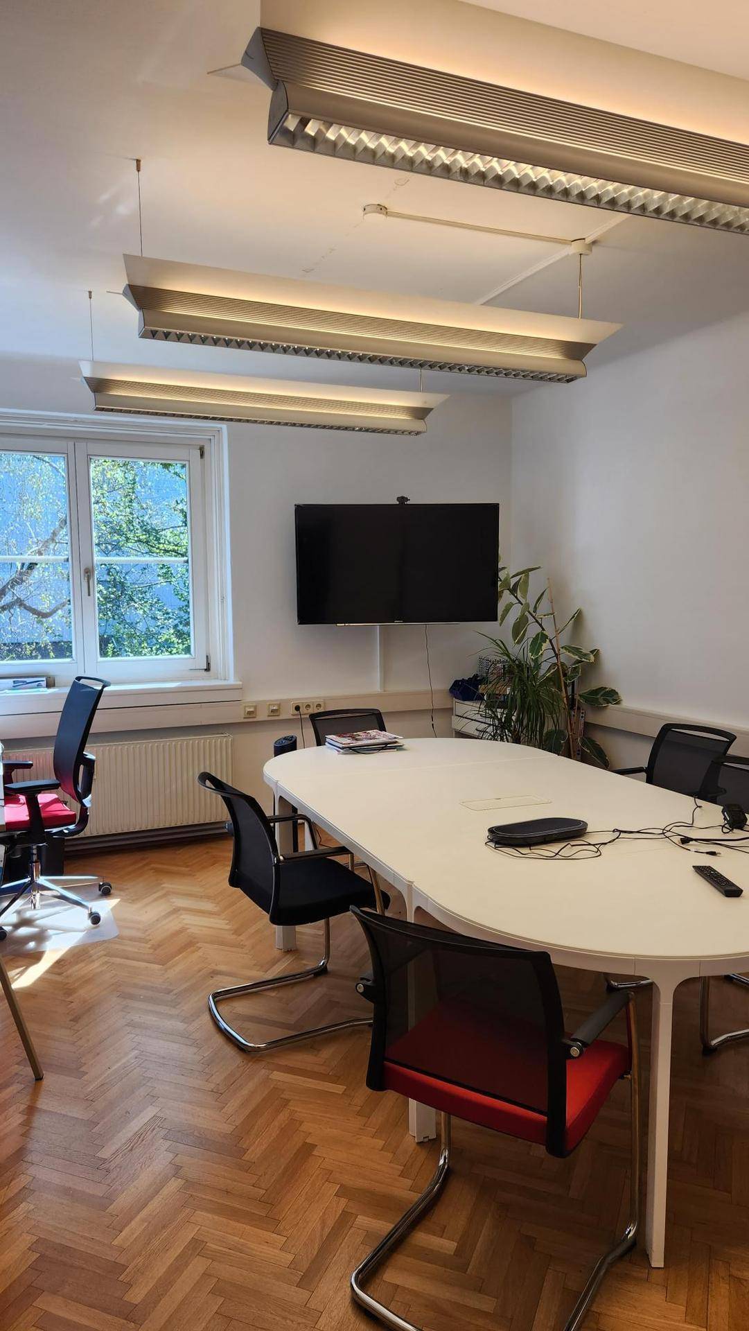 Konferenzraum mit modernem Tisch, Bürostühlen und einem großen Fenster, das viel Licht hereinlässt.