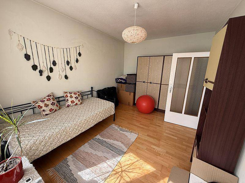 Schlafzimmer mit Holzboden, Einzelbett und Schränken, die auf den Einbau warten.