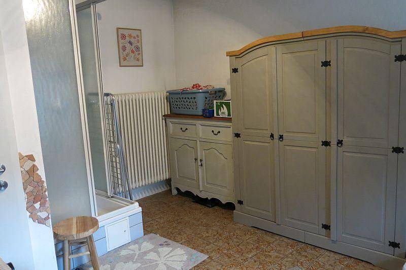 Funktionales Badezimmer mit Duschkabine, Heizkörper und einem großen Schrank, ausgestattet mit gemusterten Fliesen.