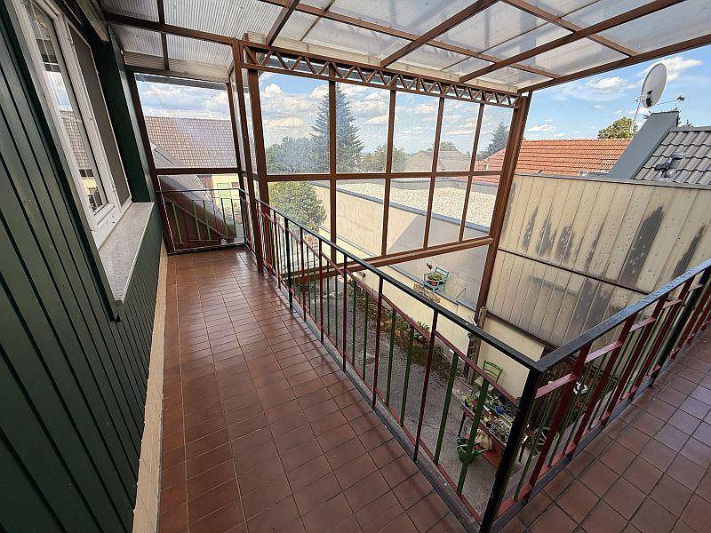 Verglaster Balkon mit Fliesenboden und Blick auf die Umgebung.