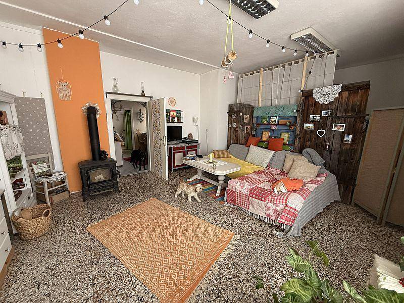 Geräumiges Wohnzimmer mit Holzofen, Terrazzoboden und farbenfrohen Textilien.