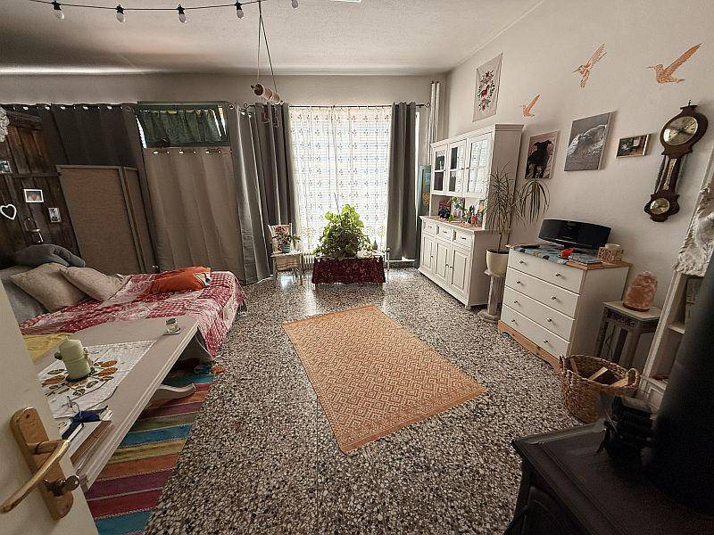 Wohnzimmer mit Terrazzoboden, großem Fenster und einem gemütlichen Schlafsofa.