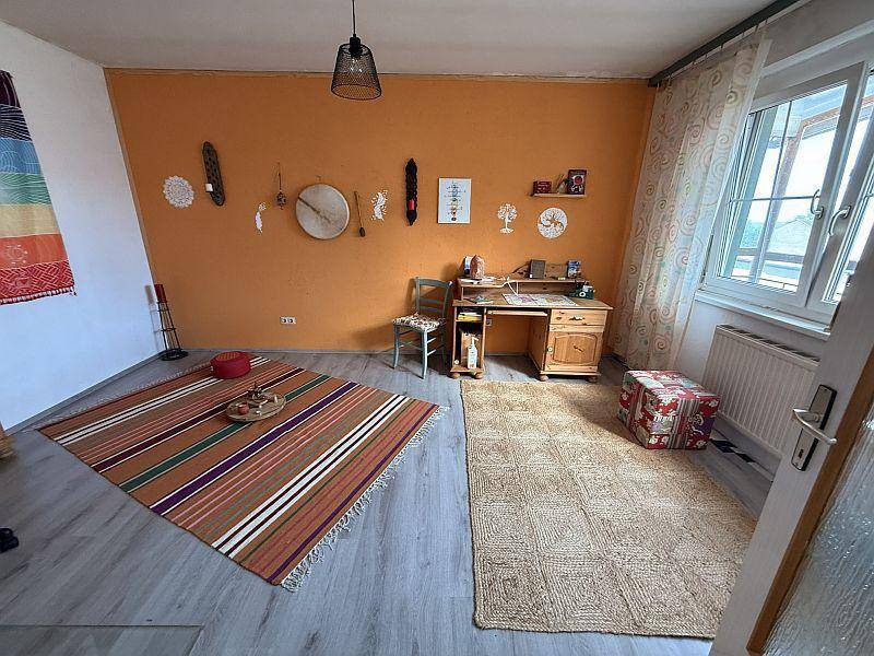 Arbeitszimmer mit orangefarbener Wand, Holzboden und einem Schreibtisch am Fenster.