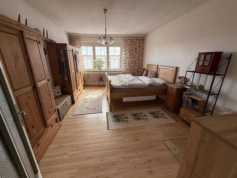 Geräumiges Schlafzimmer mit Holzboden, Doppelbett und großen Holzschränken.