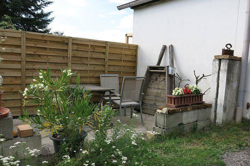 Gemütliche Terrasse mit Holzzaun, Gartenmöbeln und Pflanzen im Topf.