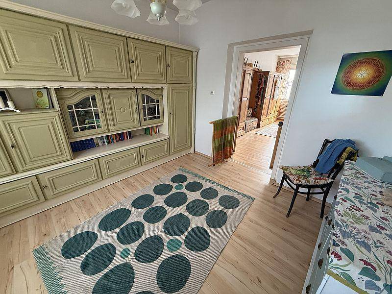 Wohnbereich mit großem Einbauschrank, Holzboden und einem gemusterten Teppich.