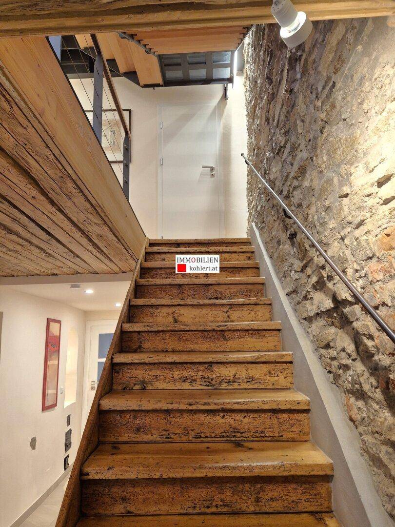 Rustikale Holztreppe mit Metallgeländer und freiliegender Steinwand.