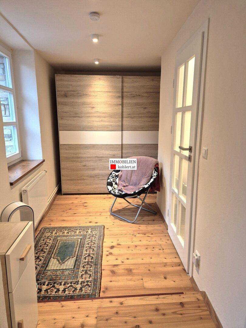 Flur mit Holzdielenboden, modernem Kleiderschrank und einem Fenster.