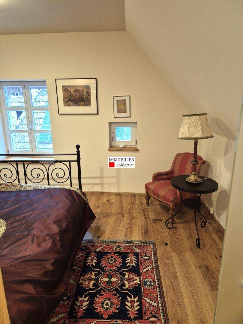 Gemütliches Schlafzimmer mit Holzboden, schmiedeeisernem Bett und traditionellem Teppich.