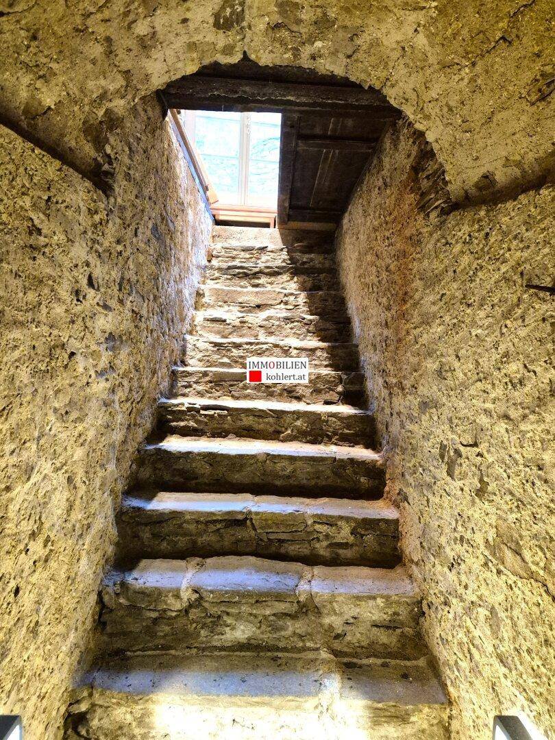 Historische Steintreppe führt durch einen gewölbten Durchgang nach oben.