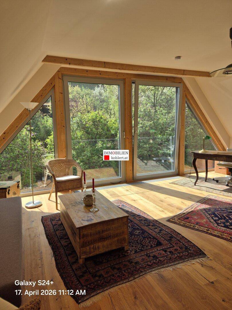 Geräumiges Wohnzimmer mit Holzboden, großen Fenstern und einem Schreibtischbereich.