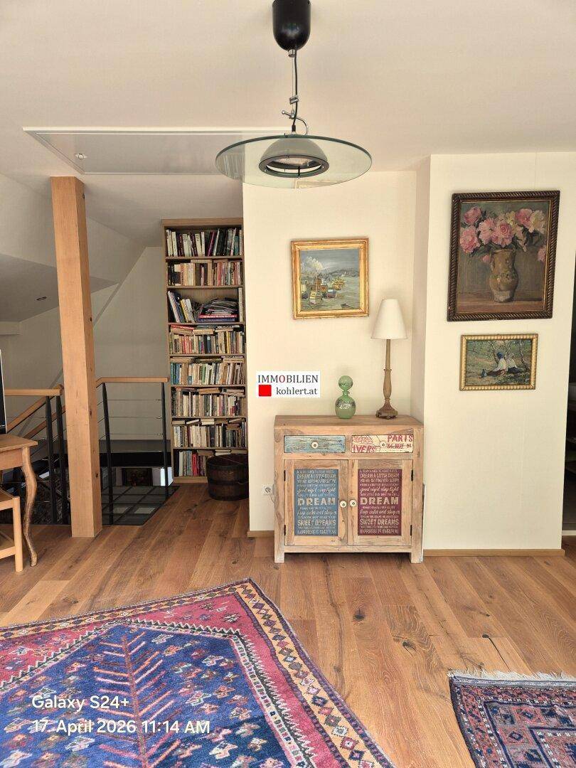 Wohnbereich mit Holzdielenboden, Bücherregal und dekorativen Möbeln.