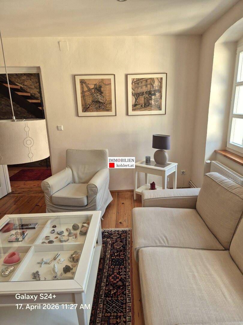 Gemütliches Wohnzimmer mit Holzdielenboden, beigen Sofas und traditionellen Teppichen.