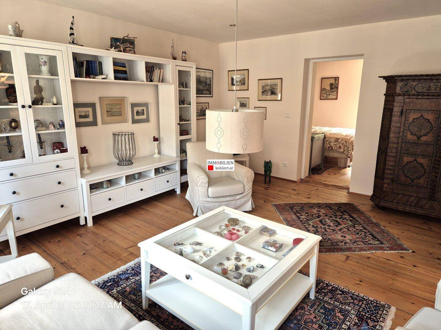 Geräumiges Wohnzimmer mit Holzdielenboden, weißer Einrichtung und dekorativen Elementen.