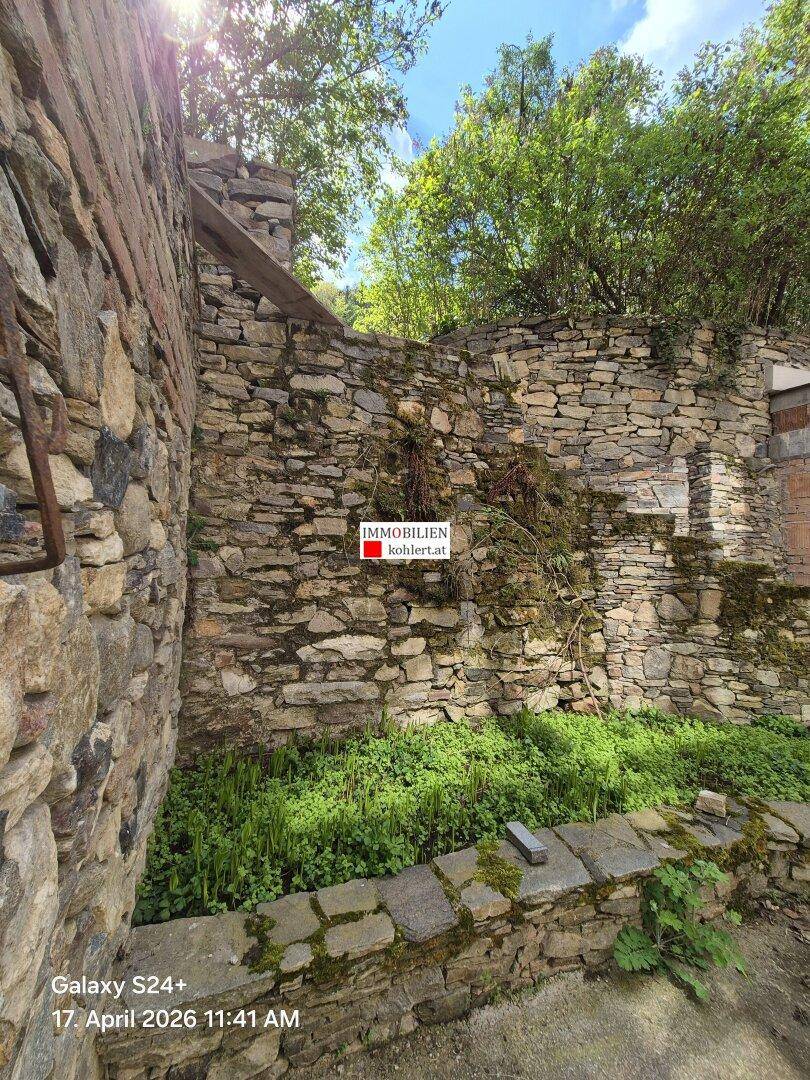 Altertümliche Steinmauern mit üppiger Vegetation und einem kleinen Gartenbereich.
