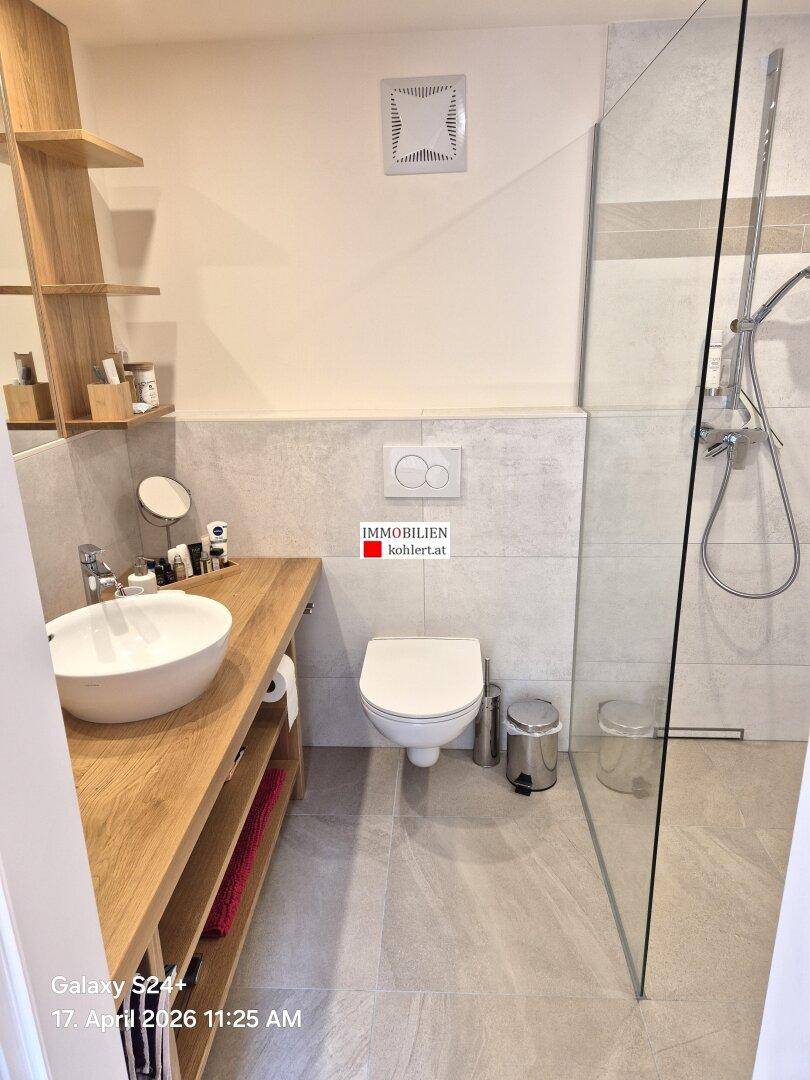 Modernes Badezimmer mit begehbarer Dusche, Holzwaschtisch und hellen Fliesen.
