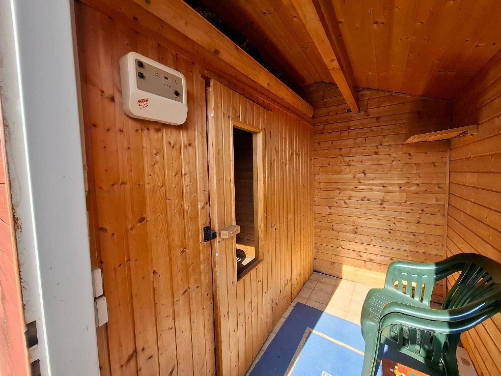 Holzvertäfelte Sauna mit Steuerungseinheit und Blick nach draußen.