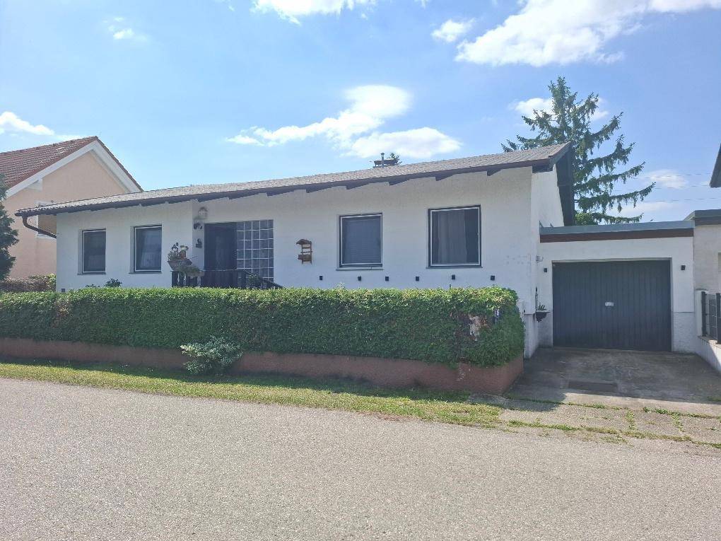 Vorderansicht des Hauses mit einer gepflegten Hecke und einer integrierten Garage.
