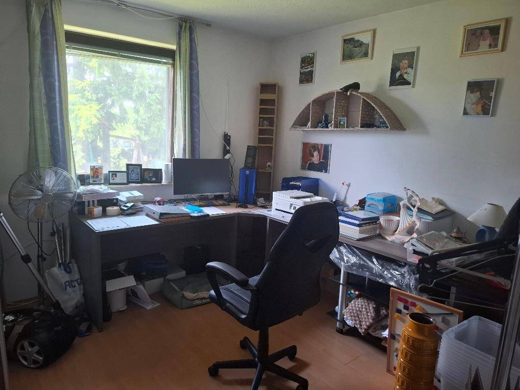 Funktionales Arbeitszimmer mit Schreibtisch, Bürostuhl und Blick ins Grüne.