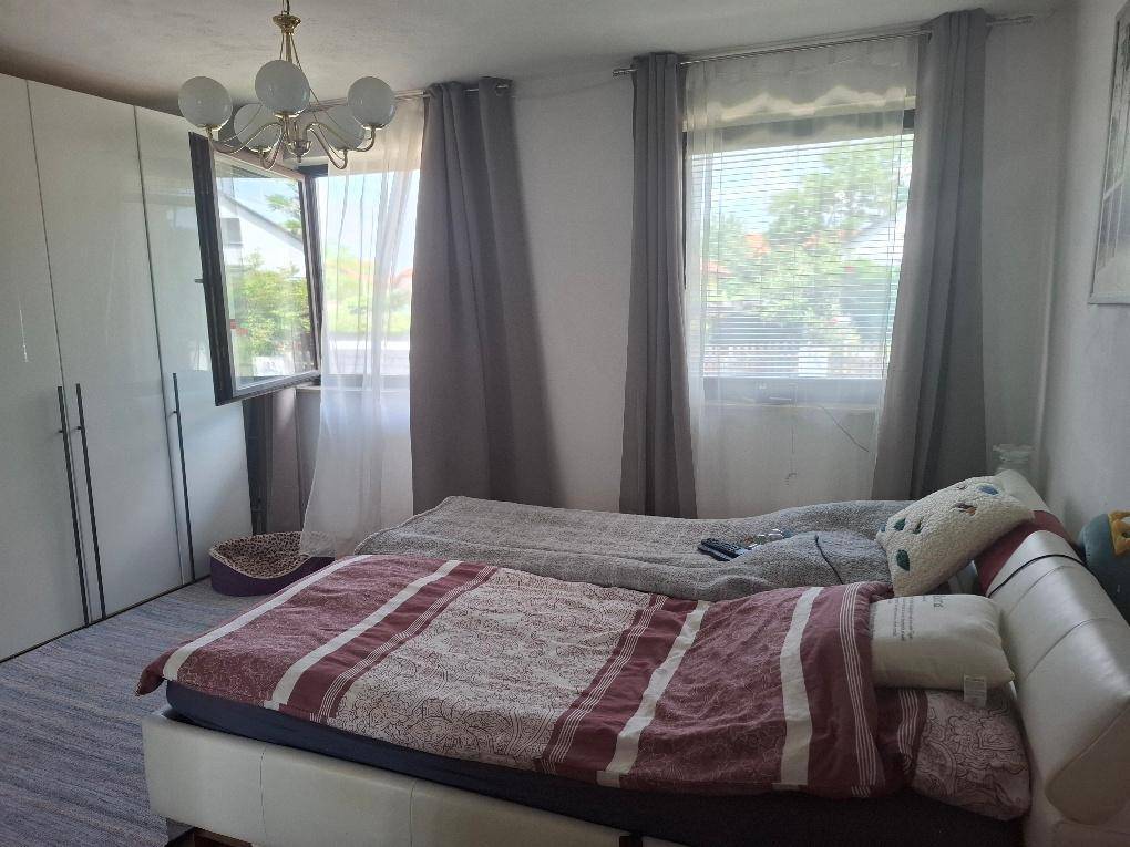 Schlafzimmer mit zwei Betten, weißen Schränken und Fenstern mit Blick nach draußen.