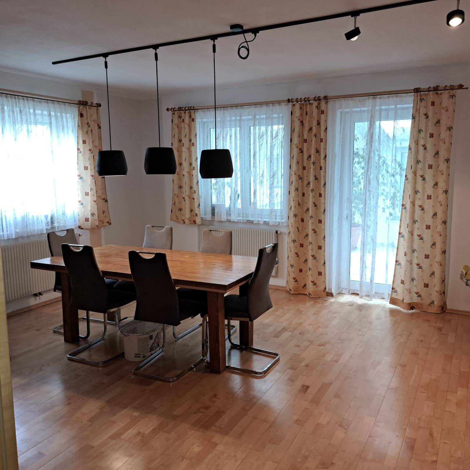 Geräumiger Essbereich mit Holztisch, modernen Pendelleuchten und hellem Parkettboden.