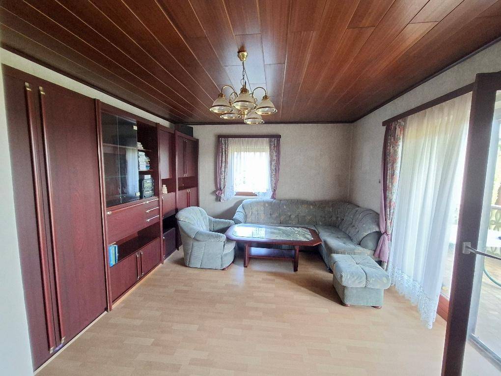 Gemütliches Wohnzimmer mit Holzdecke, Parkettboden und traditionellen Möbeln.