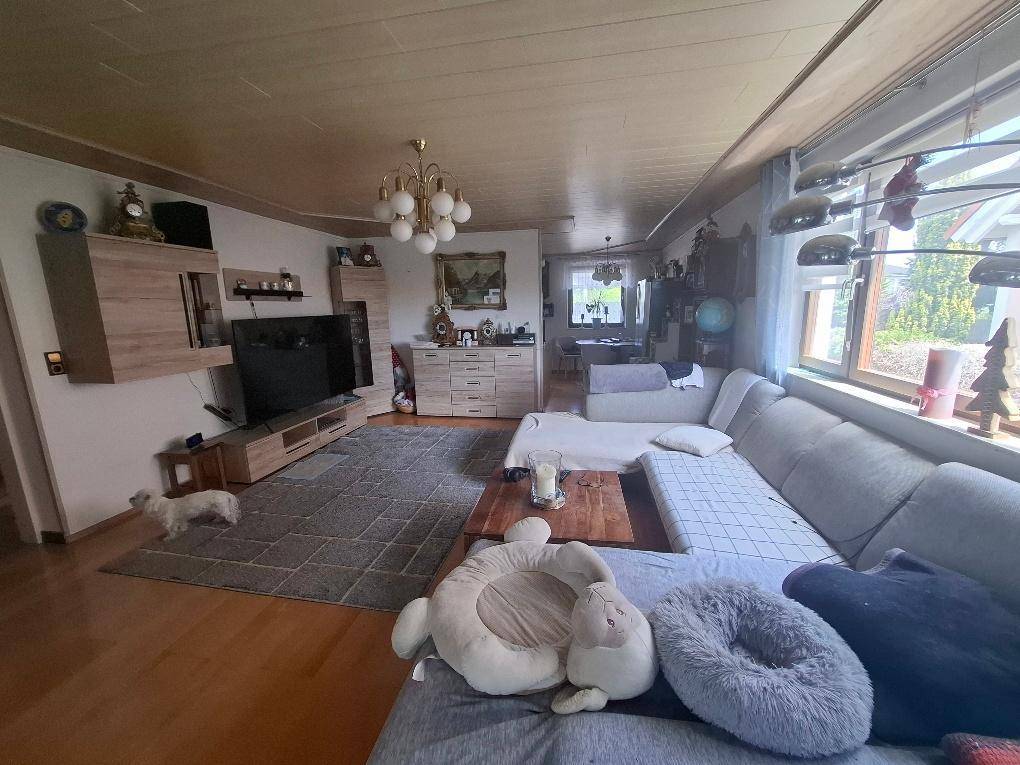 Geräumiges Wohnzimmer mit großem Sofa, Holzboden und Blick in den Essbereich.