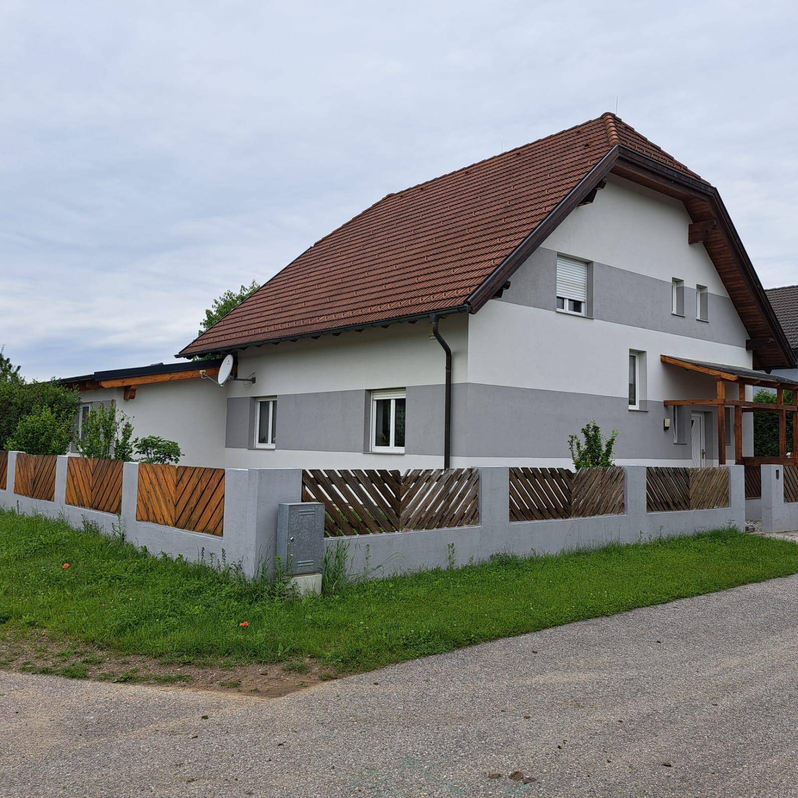 Modernes Einfamilienhaus mit zweifarbig gestrichener Fassade und Holzzaun im Vorgartenbereich.