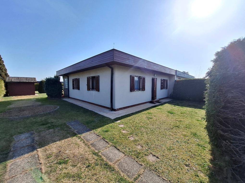 Seitenansicht des Hauses mit gepflegtem Garten, Rasenfläche und kleinen Wegen.