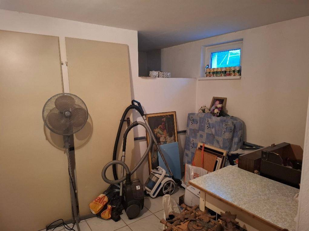 Abstellraum im Untergeschoss mit einem kleinen Fenster, Ventilator, Staubsauger und verschiedenen gelagerten Gegenständen.