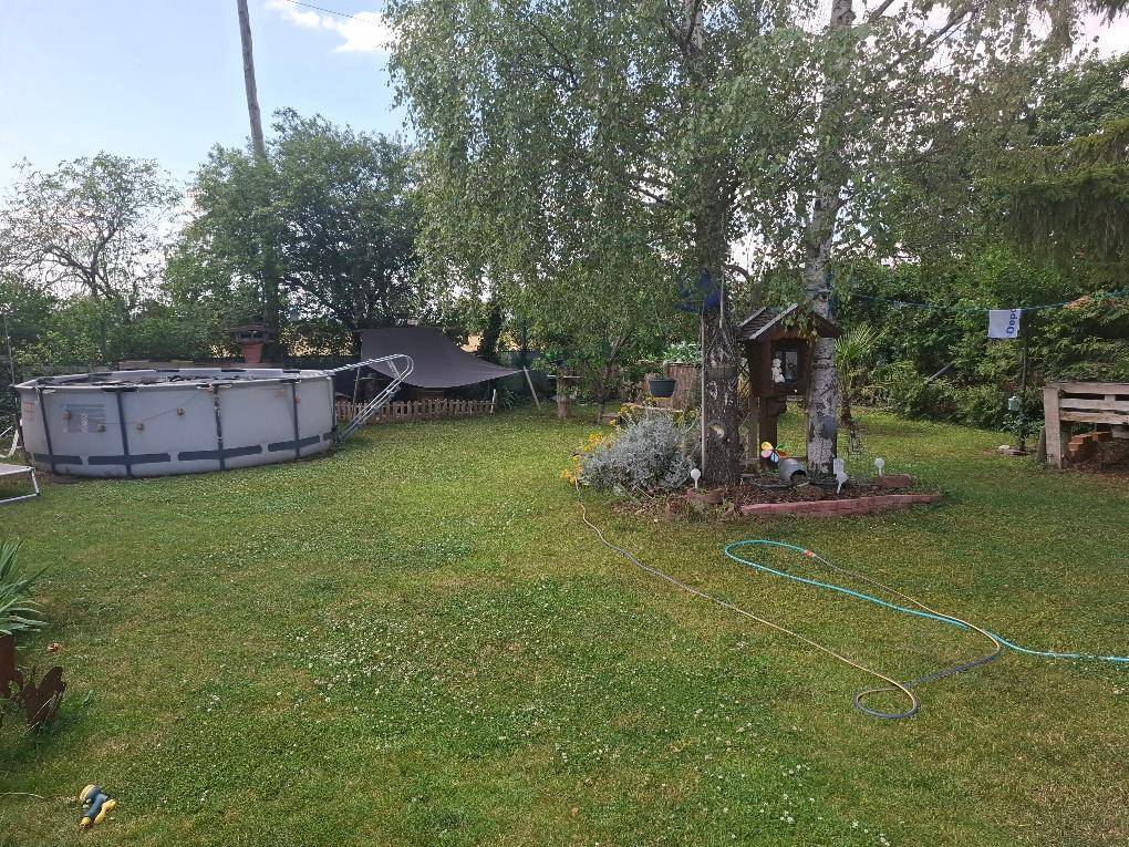 Weitläufiger Garten mit Rasenfläche, Aufstellpool und schattenspendenden Bäumen.