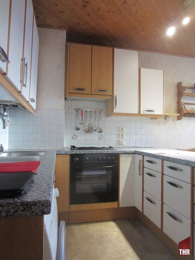 Küche mit Holzdecke, weißen Fliesen und Einbaugeräten, die eine funktionale Kochumgebung bietet.