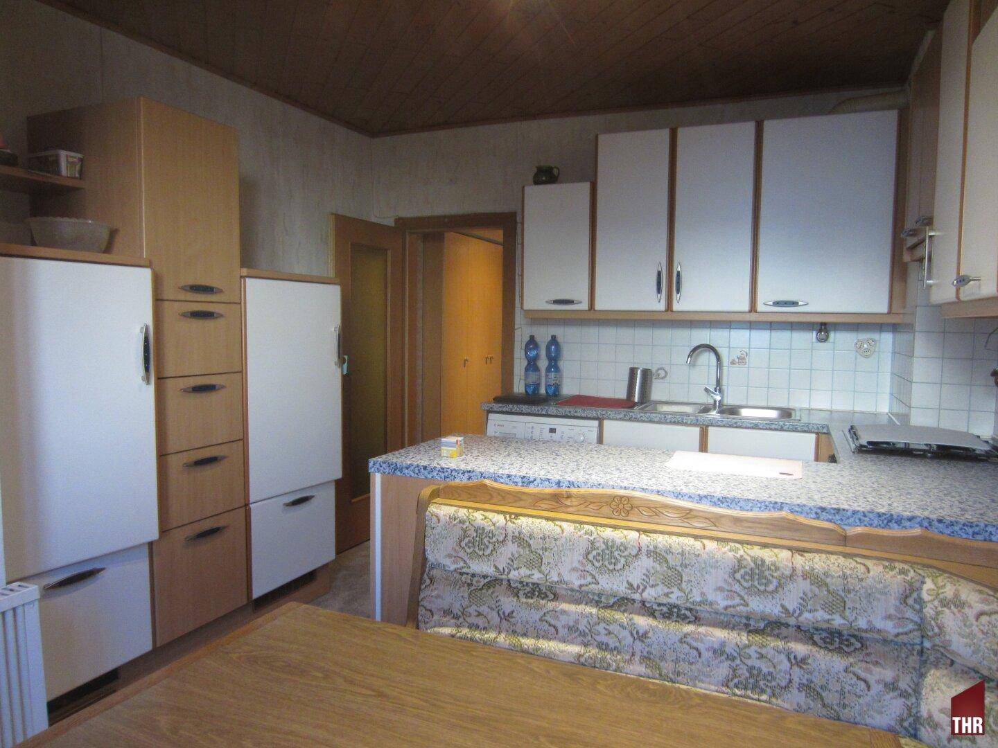 Geräumige Küche mit Essbereich, Holzdecke und integrierten Geräten, ideal für gemeinsame Mahlzeiten.