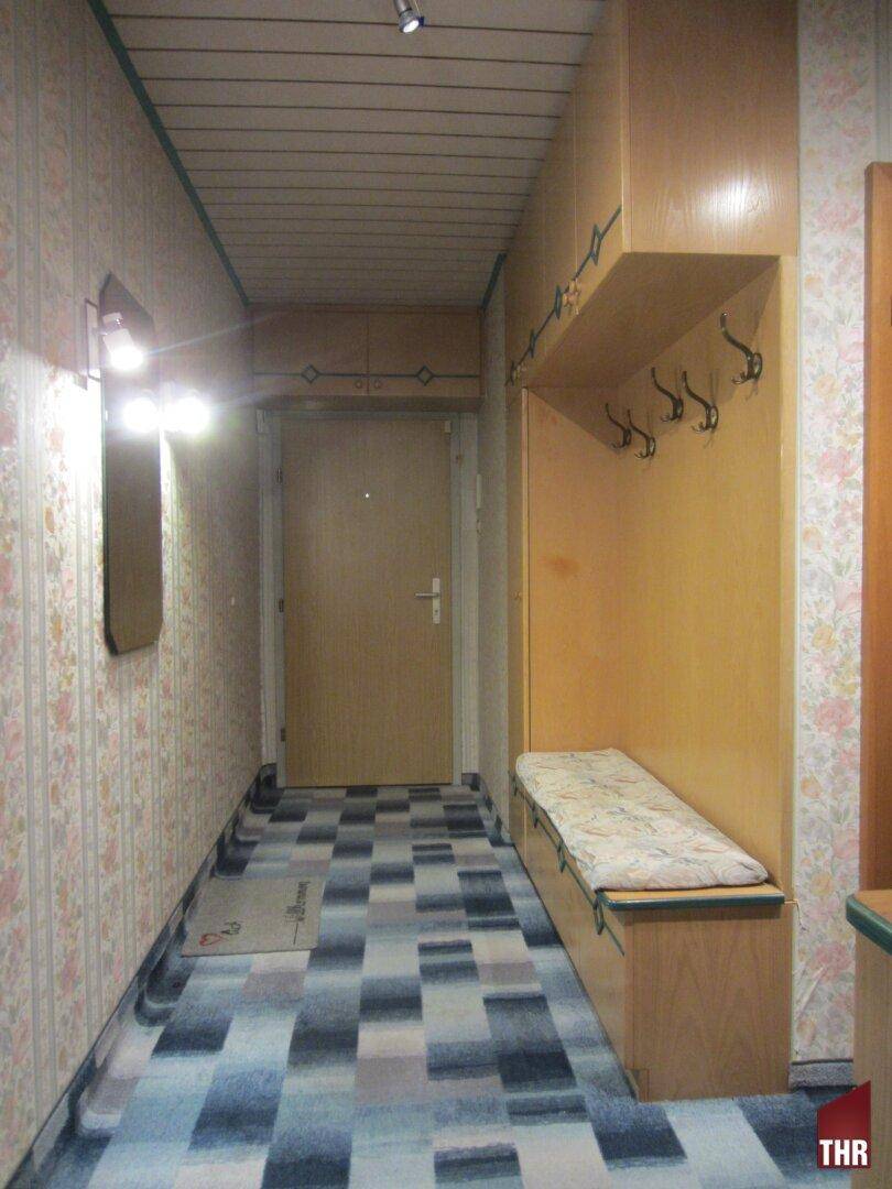 Eingangsbereich mit Garderobe, Sitzbank und gemustertem Bodenbelag, der eine einladende Atmosphäre schafft.