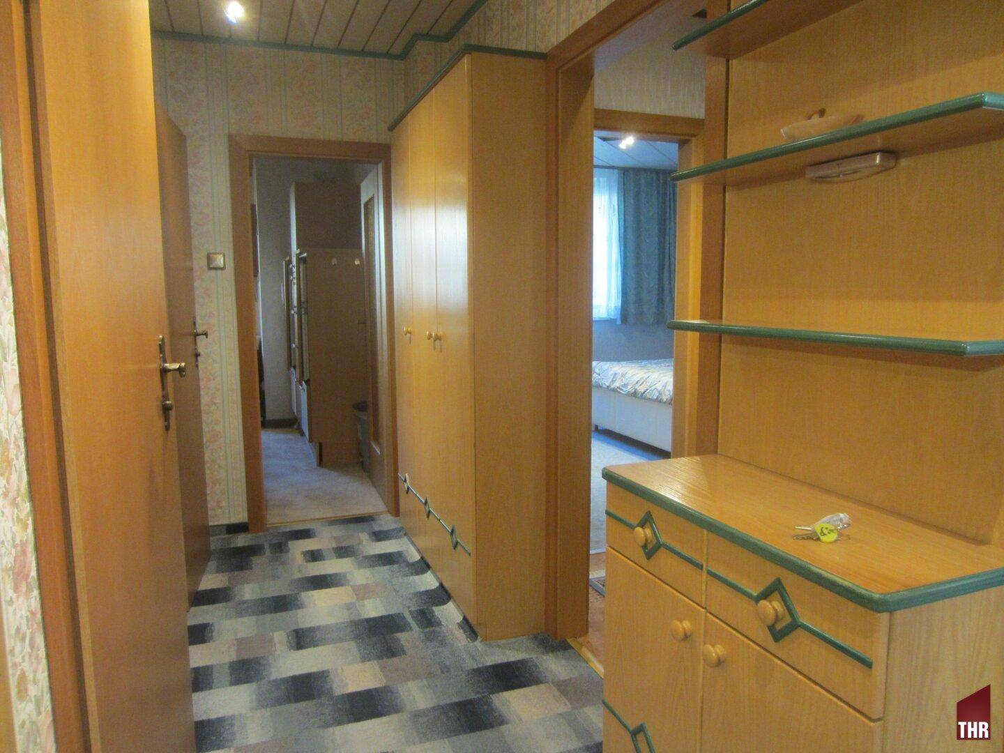 Flur mit gemustertem Boden, Holzdecke und praktischen Einbaumöbeln, die den Raum optimal nutzen.