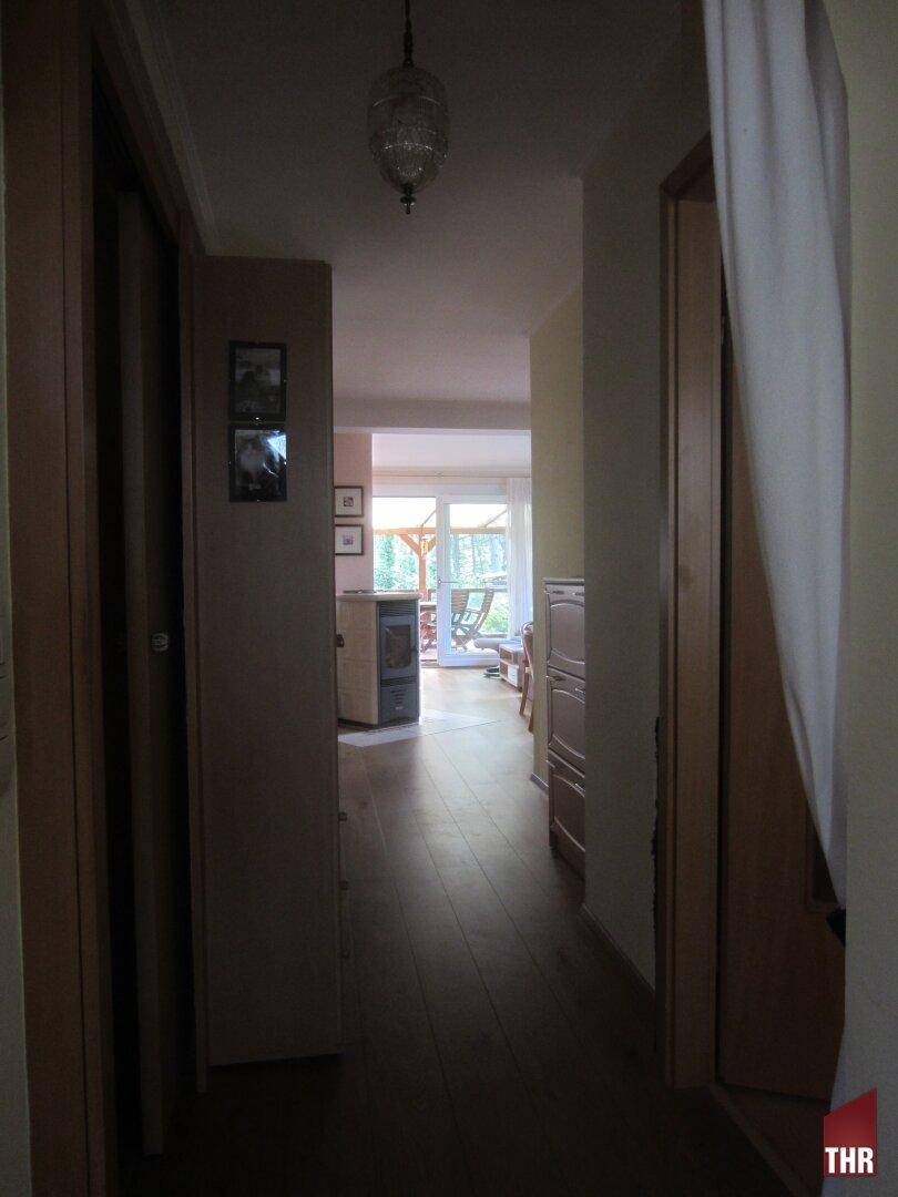 Langer Flur mit Holzboden, der zu den verschiedenen Räumen und zur Terrasse führt.